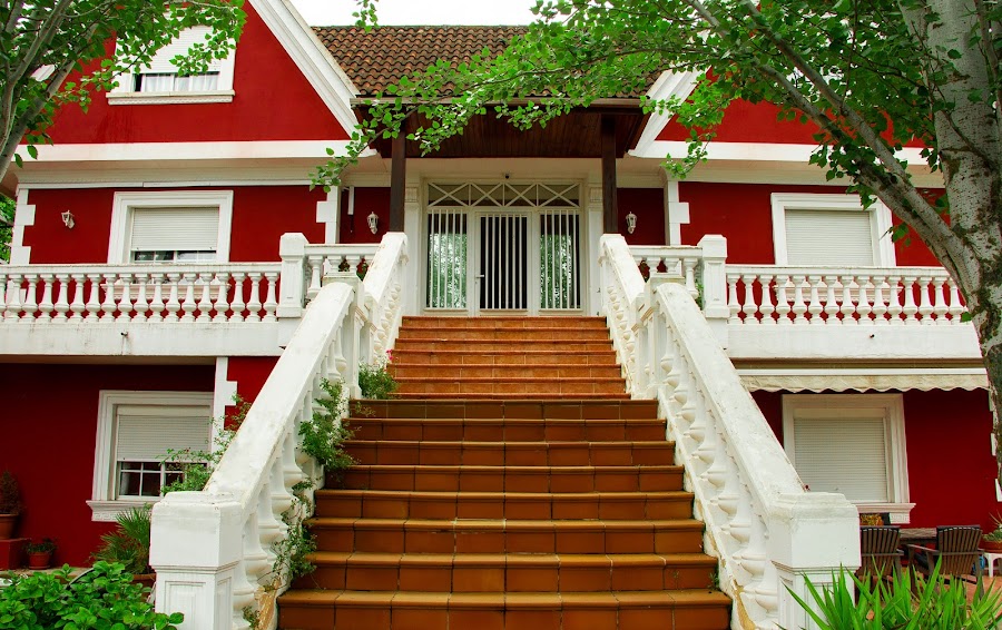 Fachada roja y blanca del centro, con escalinata de acceso y vegetación.